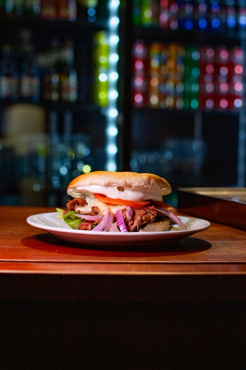 Sándwich de mechada con queso fundido y cebolla morada